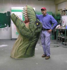 a man standing next to a fake dinosaur head