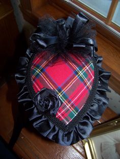 a red and black plaid hat with a rose on it's side, sitting on a table