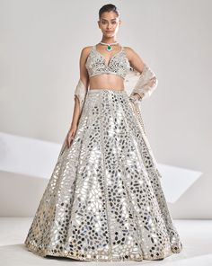 This cream raw silk lehenga features embroidery in multiple shapes and sizes of mirrors with gold thread. The blouse has a plunging neckline with all over embroidery. The dupatta has a border on all four sides.From Seema Gujral’s Samode collectionDELIVERY TIMEPlease wait 8-12 weeks for your outfit to arrive.FABRIC DETAILSRaw SilkProfessional cleaning only. Pink Sequin Lehenga, Mirror Lehenga, Sequins Lehenga, Seema Gujral, Mirror Work Lehenga, Raw Silk Lehenga, Mirror Work Blouse, Floral Lehenga, Heavy Dresses