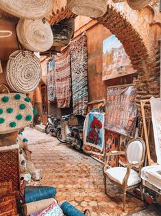 an alleyway with lots of baskets and rugs hanging from the ceiling in front of it