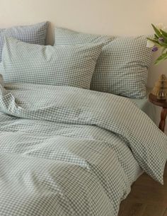 a bed with blue and white checkered comforter on it next to a night stand