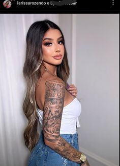 a woman with long hair and tattoos on her arm is posing for the camera,