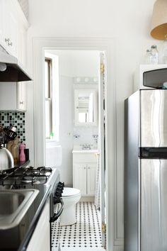 a kitchen with white cabinets and black and white tile flooring is seen in this image