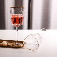 a glass filled with liquid sitting on top of a table next to a gold tray