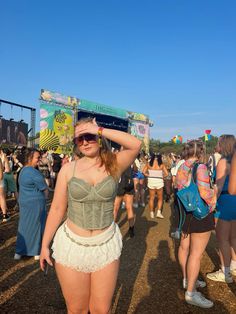 a woman standing in front of a crowd at a music festival with her hands on her head