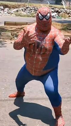 a man in a spiderman costume is standing on one leg and arms out to the side