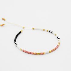 the multicolored beaded bracelet is shown on a white surface with gold accents