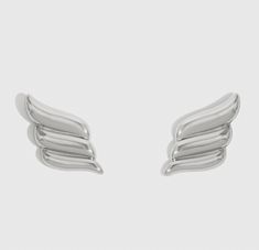 two pairs of silver earrings with wings on them, one in the shape of an angel