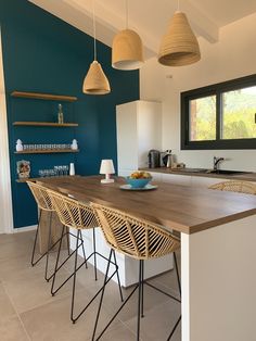 a kitchen with blue walls and wooden bar stools next to the counter top in front of an island