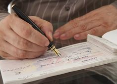 a man holding a pen and writing on a piece of paper with several other papers