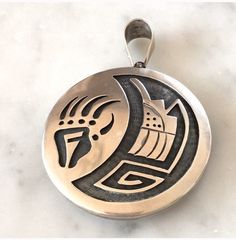 "Stunning Hopi Reversible swivel pendant.This amazing unique pendant is handcrafted with the traditional technique using two layers of Sterling silver.It have a very large bale which will fit most chains.One side depicts a Kokopelli and a dwelling and the reverse is a bear paw claw.Two unique pendants in one. Bale 5/8 × 1/2\" Measures 2 inches in diameter Weight 60 Grams Stamped Sterling New,never worn from vintage 1980's collection." Traditional Polished Medallion Jewelry, Traditional Medallion Jewelry With Polished Finish, Artisan Medallion Jewelry With Large Pendant, Artisan Jewelry With Large Medallion Pendant, Artisan Polished Round Pendant Jewelry, Artisan Jewelry With Polished Round Pendant, Artisan Round Pendant Jewelry With Polished Finish, Artisan Round Pendant With Polished Finish, Unique Artistic Round Pendant Jewelry