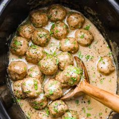 a wooden spoon in a slow cooker filled with meatballs and gravy