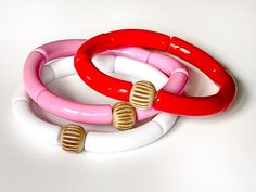 This colorful red and pink bracelet set of 3 is perfect for stacking and mixing and matching year round. The skinny acrylic tubes allow for multiple bracelets to be worn in a comfortable stack all day. Each set comes with a pink, red and white bracelet. Acrylic bracelets are 7 3/4 inches in diameter and fit most women (size medium). If you have a smaller wrist, these will slide a bit more like a bangle (tip: the more you stack, the less they slide). Each bracelet is made of 8mm acrylic tube beads and finished with a bone bead to complete the look. Stack, mix and match, and have fun with these beauties! Materials: - Acrylic - Bone Packaging: All jewelry is handmade in Chattanooga, TN and packaged in a white jewelry box with black and white gingham bow - ready to gift or unwrap yourself! --- Trendy Red Plastic Bracelets, Trendy Red Plastic Bracelet, Red Plastic Beaded Bracelets As Gift, Trendy Red Stackable Beaded Bracelets, Trendy Red Stackable Bracelets, Adjustable Red Beaded Plastic Bracelets, Stacked Beaded Bracelets, Bracelets Pink, Bright Jewelry