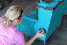 a woman in pink shirt painting a blue chair