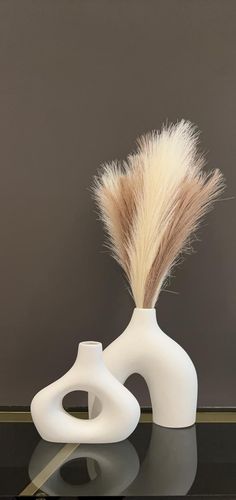 a white vase sitting on top of a table next to a brown and white feather