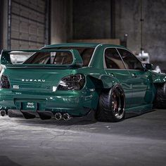 two green cars parked next to each other in a garage