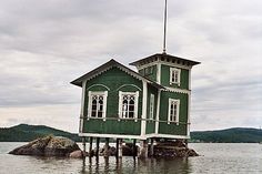 a green house sitting on top of a body of water