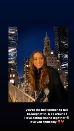 a woman with long hair standing in front of a cityscape and smiling at the camera