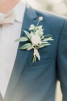 a man in a blue suit with a white flower on his lapel and bow tie