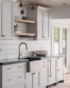 a kitchen with white cabinets and black counter tops, gold pulls on the faucet