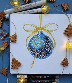 a blue and gold christmas ornament on a white card surrounded by golden decorations