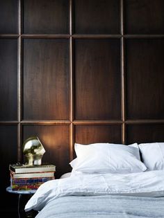 a bed with white sheets and pillows next to a painting on the wall above it