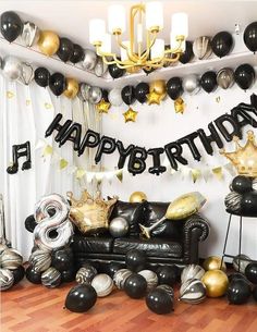 a room filled with black and gold balloons, foil streamers, and birthday decorations