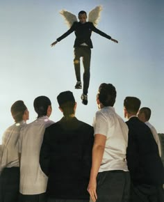 a man flying through the air while standing on top of a group of other people