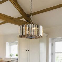 a chandelier hanging from the ceiling in a room with white walls and wood beams