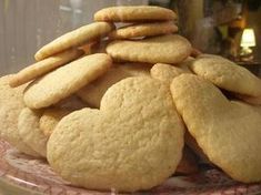 a pile of cookies sitting on top of a pink plate next to a glass container