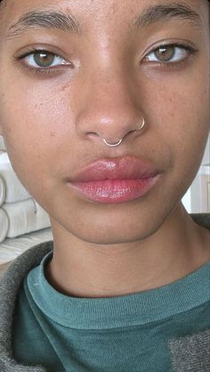 a close up of a person with a nose piercing on their nose and wearing a sweater