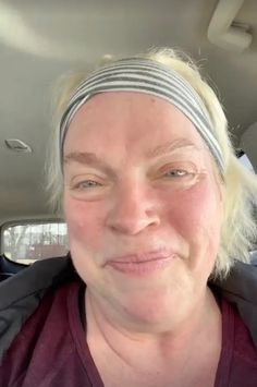 a woman with blonde hair wearing a headband in the back seat of a car