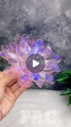 a hand holding a plastic flower with lights on it