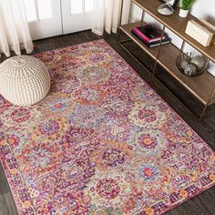 a colorful area rug with an ornate design on the floor and side table next to it