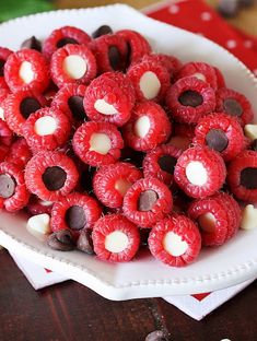 a white bowl filled with red raspberries and chocolate chips on top of a wooden table