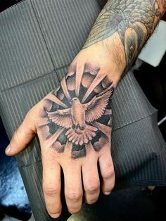 a man's hand with a bird and cross tattoo on the middle of it