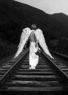 an angel is walking down the railroad tracks