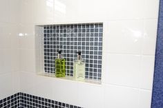 two bottles are sitting in the corner of a bathroom mirror with blue and white tiles