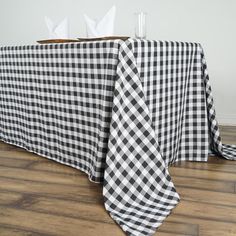 a black and white checkered tablecloth with napkins on it sitting on a wooden floor