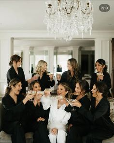 a group of women sitting on top of a couch holding wine glasses in their hands