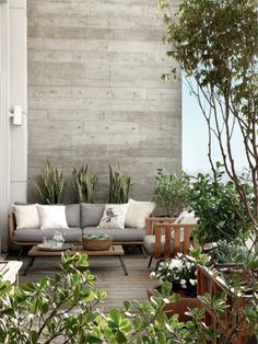 an outdoor living area with couches and potted plants