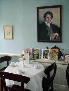 there is a table with two cups and saucers on it in front of a painting