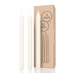 two white candles sitting in front of a cardboard box