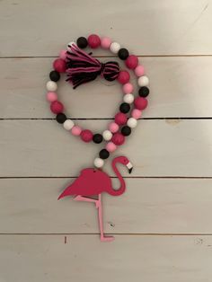 a pink and black beaded necklace with a flamingo charm hanging from it's side