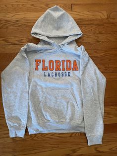 50/50 Cotton Poly 8oz Unisex Light Grey Florida Lacrosse Hoodie Available in adult sizes only S, M, L,XL Lacrosse Outfits, Lacrosse Practice, Lacrosse Sweatshirt, Lacrosse Hoodie, College Hoodies, Baltimore Md, Florida Gators, Cute Fits, Lacrosse