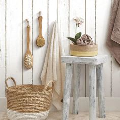 a white wooden wall with some baskets and spoons on the table next to it