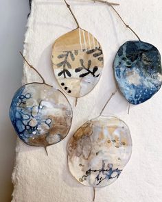 three handmade ceramic plates hanging on a white wall next to a piece of paper