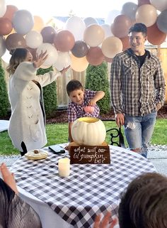 a young boy and woman standing in front of a table with balloons