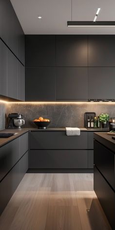 a modern kitchen with black cabinets and wood flooring is lit by recessed lighting