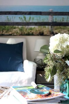 a vase with white flowers sitting on top of a coffee table next to a couch